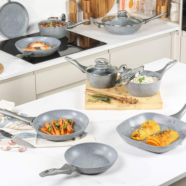 Set of grey non-stick pans and pots with lids on kitchen counter, some with food inside