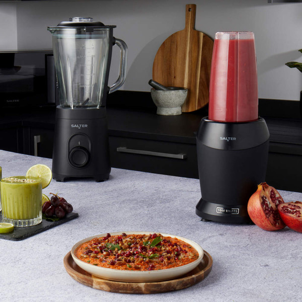 Salter black blender and smoothie maker on kitchen worktop with green juice, red smoothie, and pizza.