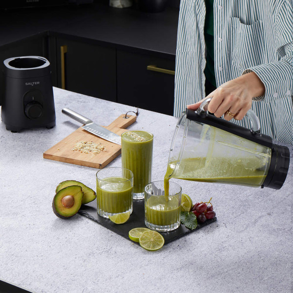 Salter blender pouring green smoothie into glass with avocado, lime and grapes on kitchen counter