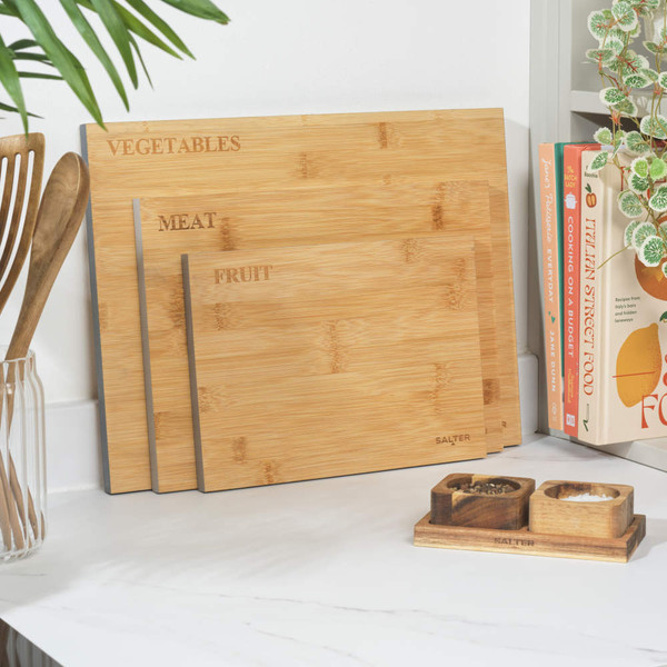 Set of three bamboo chopping boards for meat, fruit, and vegetables on a kitchen counter