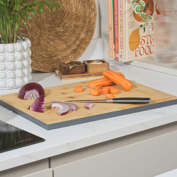 Bamboo chopping board with cut carrot and red onion on kitchen counter