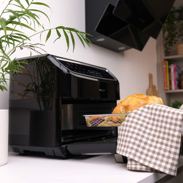 Black digital air fryer oven on kitchen counter with cooked chicken in basket