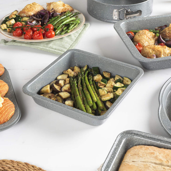 Set of grey non-stick bakeware including trays, tins, roaster and muffin pan on kitchen counter
