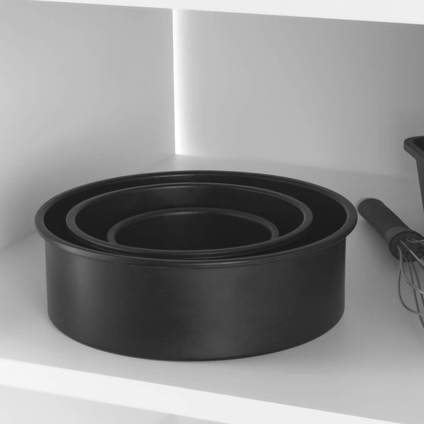 Set of three black round cake tins with whisk and loaf tin on shelf
