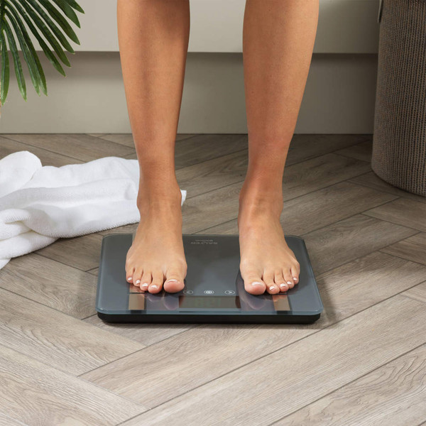 Person standing on black digital bathroom scale on wood floor