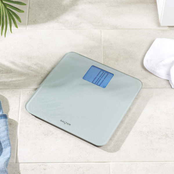 Silver digital bathroom scale with large backlit display, shown at an angle.