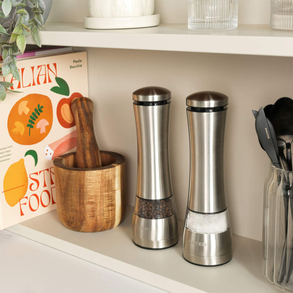 Set of stainless steel salt and pepper mills on kitchen shelf