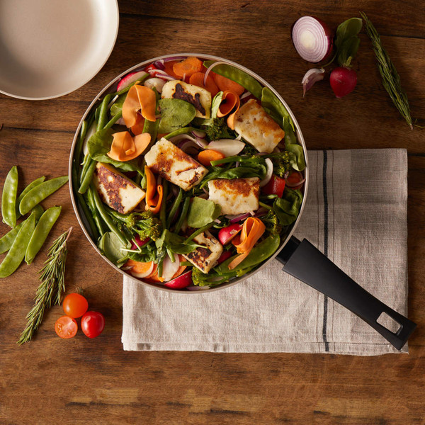 Frying pan with grilled halloumi and fresh vegetables on wooden table