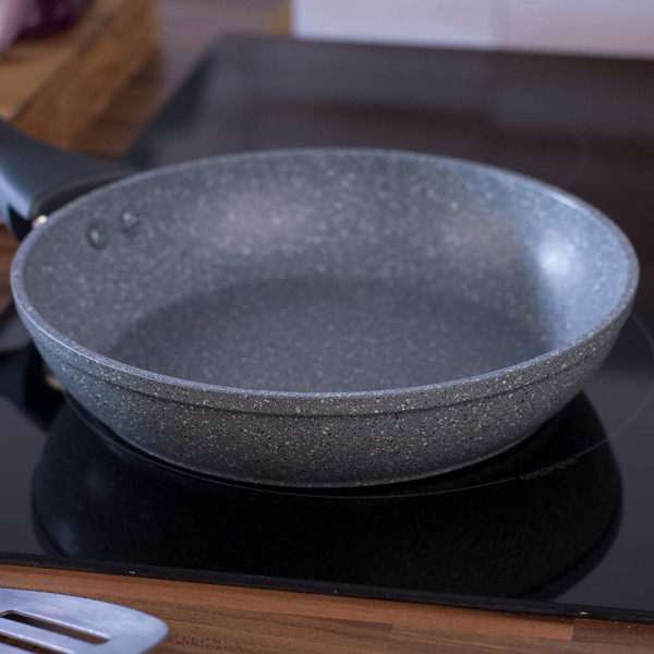 Grey non-stick frying pan on hob, angled view