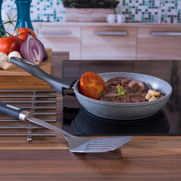 Grey non-stick frying pan with steak, tomato, onion and mushrooms on induction hob