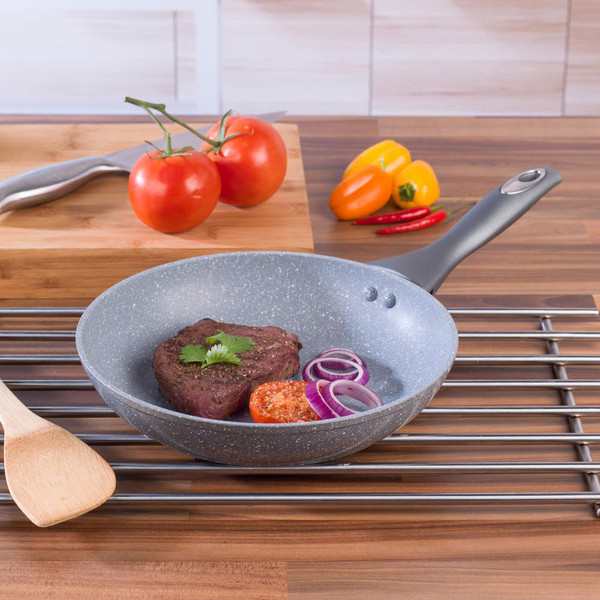 Grey non-stick frying pan with steak, tomato, and red onion on wooden kitchen surface