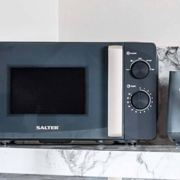 Grey microwave oven with gold handle, door open, showing manual dials