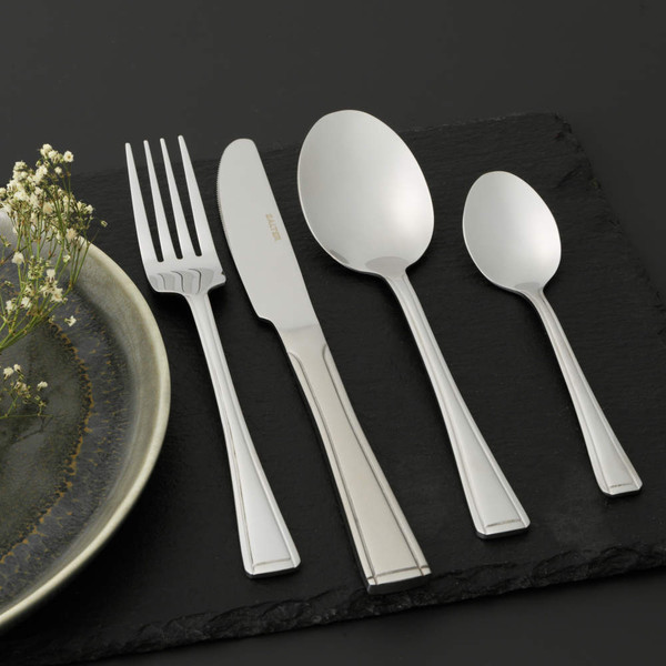 Set of four silver stainless steel cutlery pieces on slate: fork, knife, dessert spoon, teaspoon.