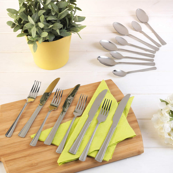 Stainless steel cutlery set with forks, knives, and spoons on chopping board and napkin