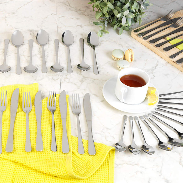 Polished stainless steel cutlery set shown with tea and macarons on marble surface