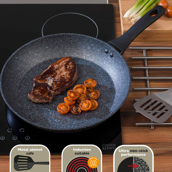 Grey non-stick frying pan on induction hob with steak and grilled cherry tomatoes