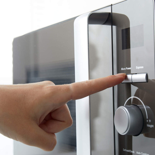 Hand pressing microwave oven start button