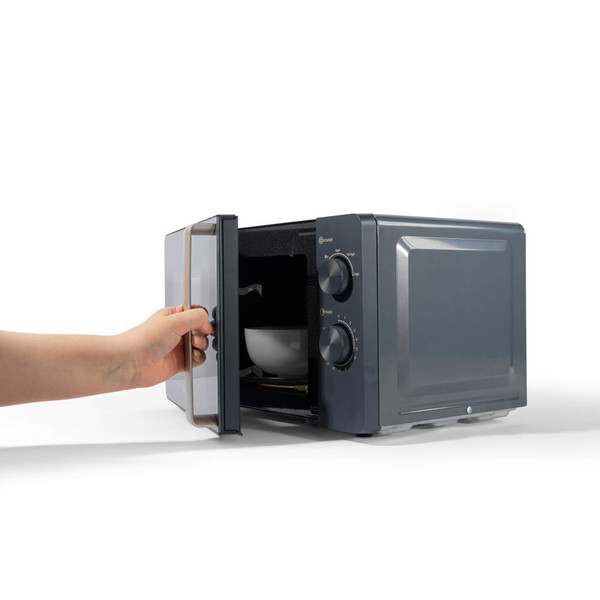 Black microwave oven with door open, hand placing a bowl inside
