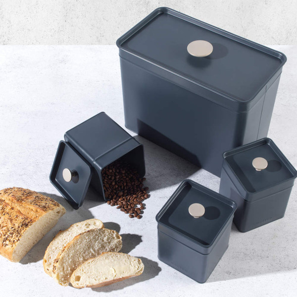 Set of dark grey metal storage canisters with bread and coffee beans, kitchen counter.