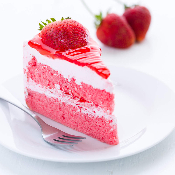 Slice of strawberry cake with cream filling, strawberry glaze, and fresh strawberry on top.