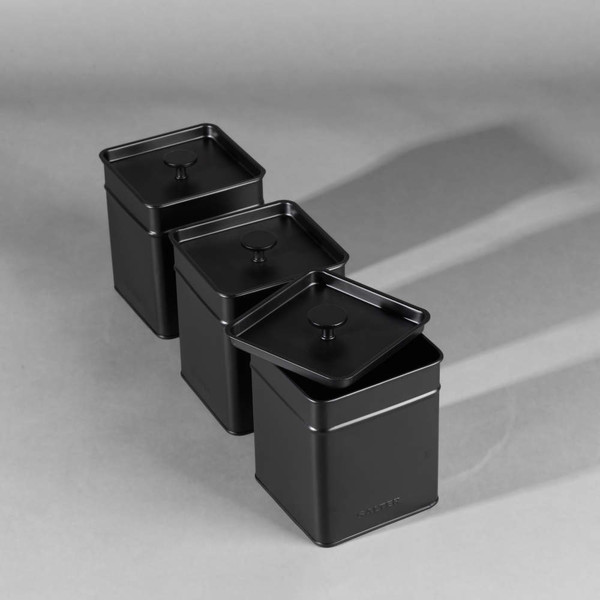 Set of three black metal storage canisters with lids, shown in a row.