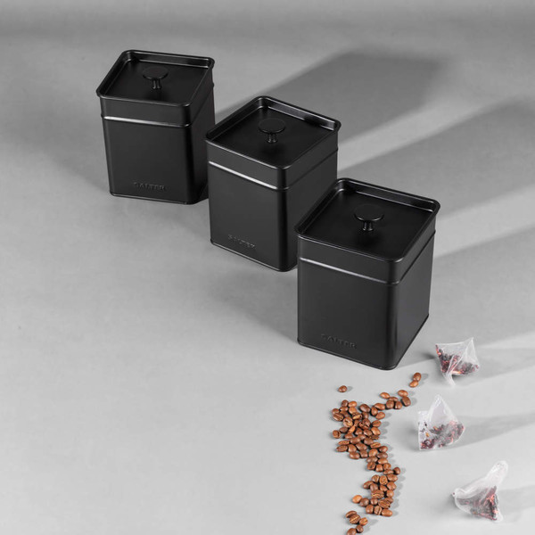 Black electric kettle pouring hot water into glass mug with tea bag on kitchen counter