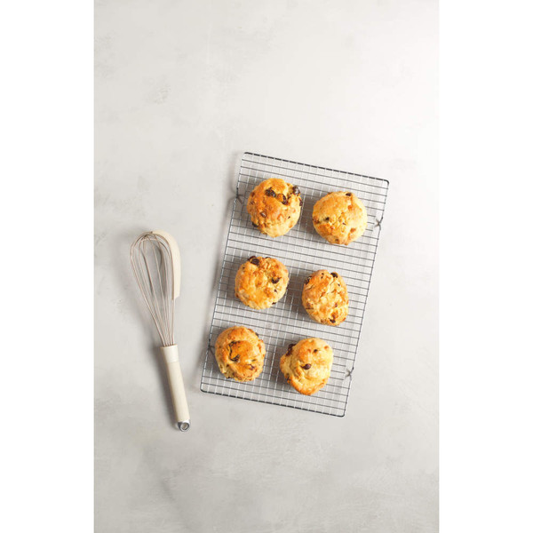 Six fruit scones cooling on a wire rack with whisk, shown for bakery bakeware.