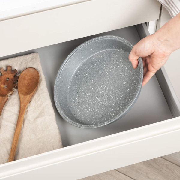 Grey speckled roasting tin placed in kitchen drawer beside two wooden utensils