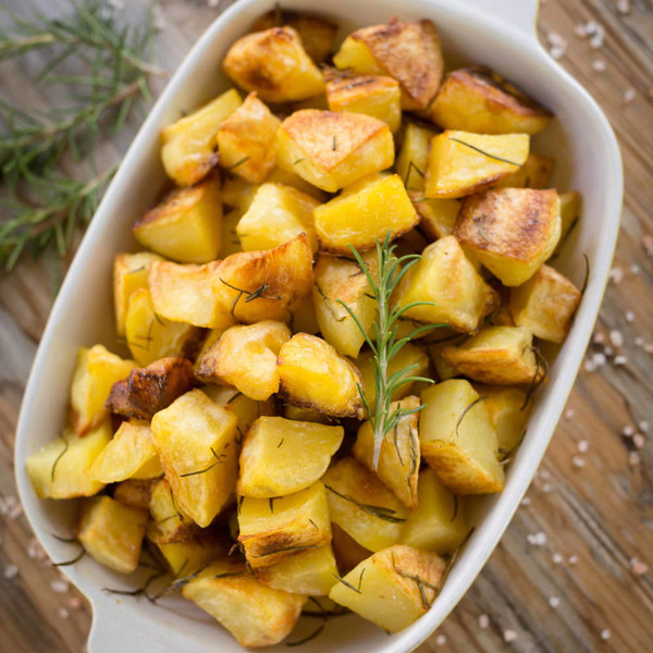 Roast potatoes with rosemary in white serving dish