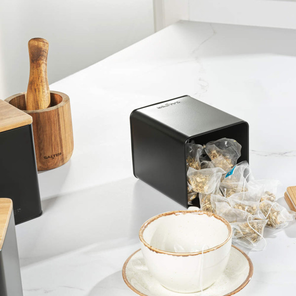 Black kitchen appliance set with wood accents, including kettle, toaster, microwave and storage jars.