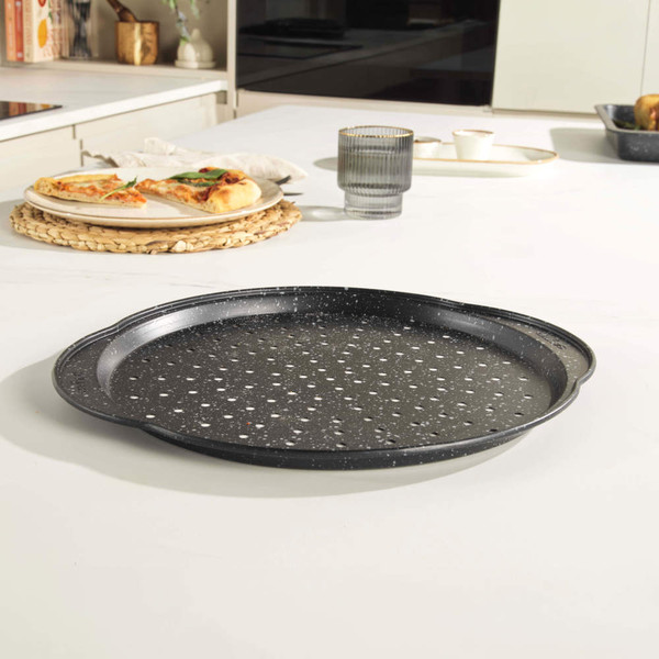 Grey non-stick pizza tray with perforated base on kitchen counter