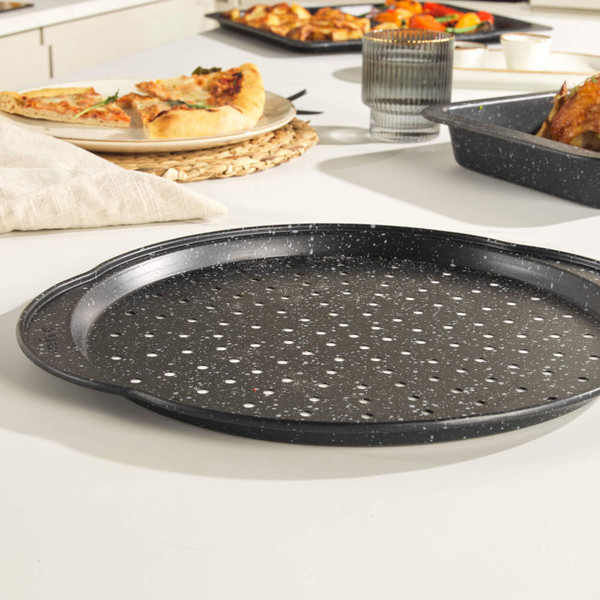 Black non-stick perforated pizza tray on a kitchen counter