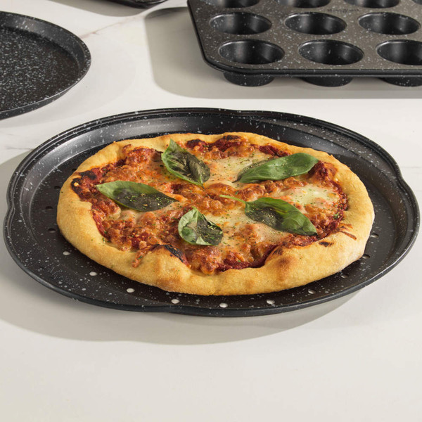 Round margherita pizza with basil leaves shown on black speckled pizza tray