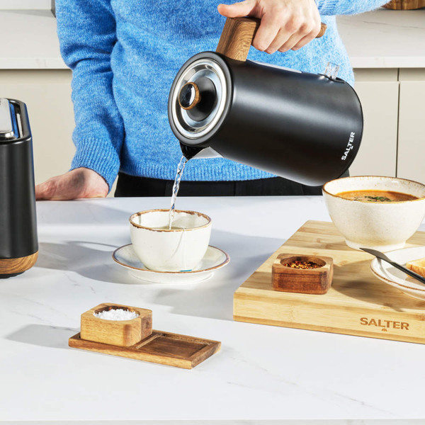 Black 4-slice toaster with wood effect, shown toasting bread in a modern kitchen
