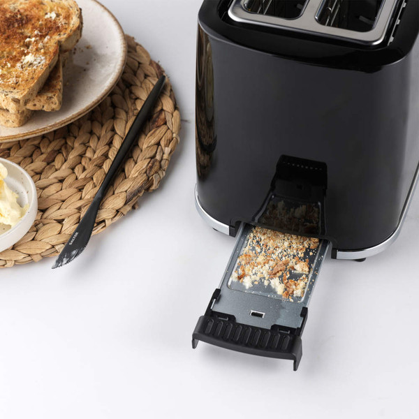 Black toaster with removable crumb tray, shown beside buttered toast. Product feature image.