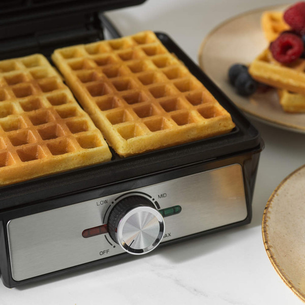 Black waffle maker with two golden waffles, lid open, showing temperature dial