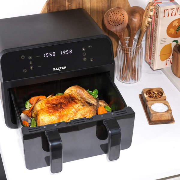 Black digital air fryer with sweet potato fries in one drawer, hand removing divider