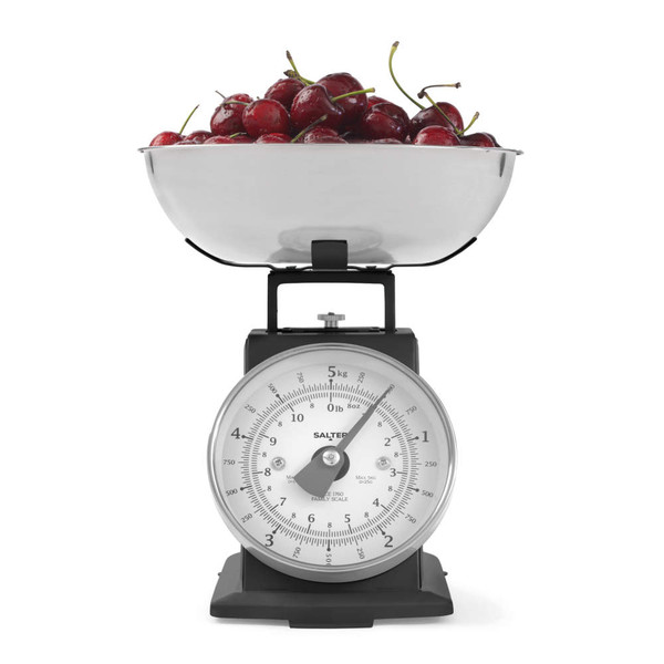 Black mechanical kitchen scale with stainless steel bowl filled with cherries