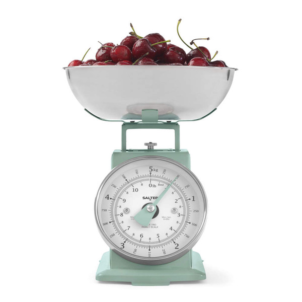 Green mechanical kitchen scale with stainless steel bowl of fresh cherries