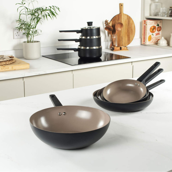 Set of three non-stick frying pans, black with taupe interior, shown on kitchen worktop
