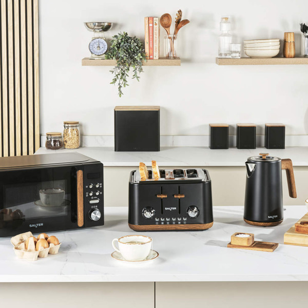 Black bread bin set with wooden lids on kitchen counter, loaf of bread inside bin
