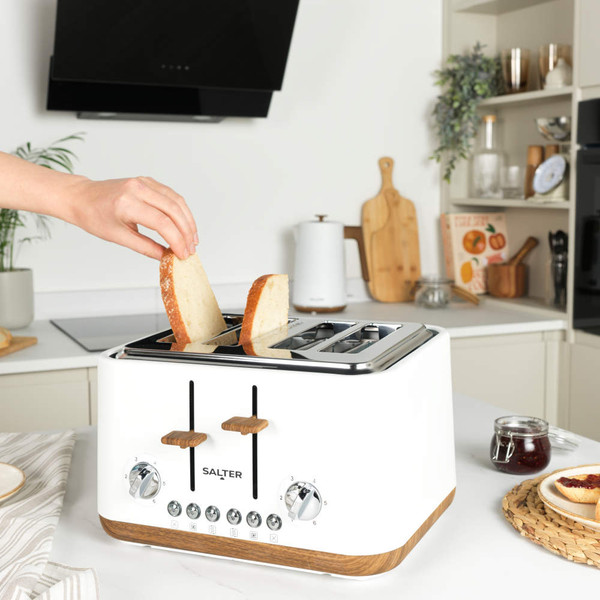 White 4-slice toaster with wooden accents on kitchen counter, hand adjusting controls