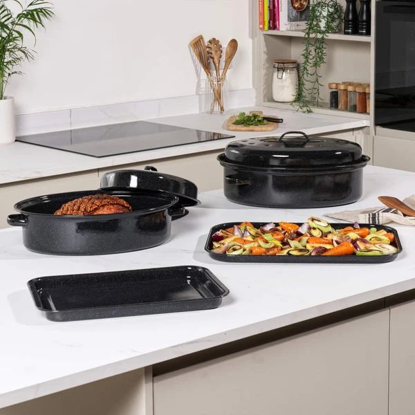 Black enamel roasting tray with mixed roasted vegetables, shown on kitchen worktop