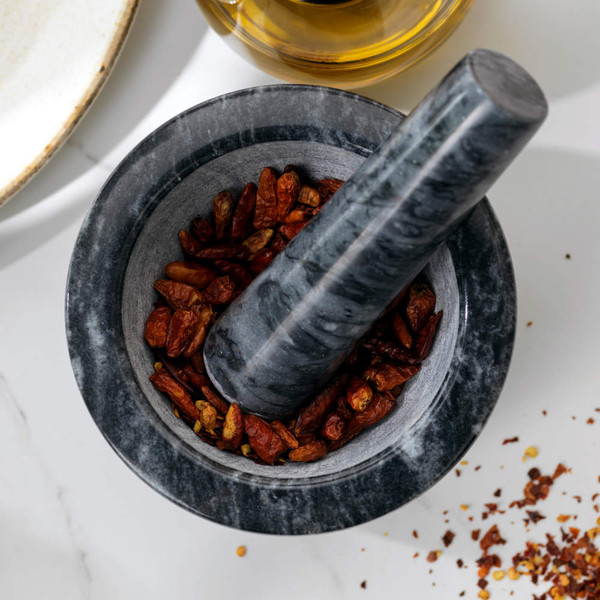 Grey marble pestle and mortar with dried chillies, for grinding spices in the kitchen