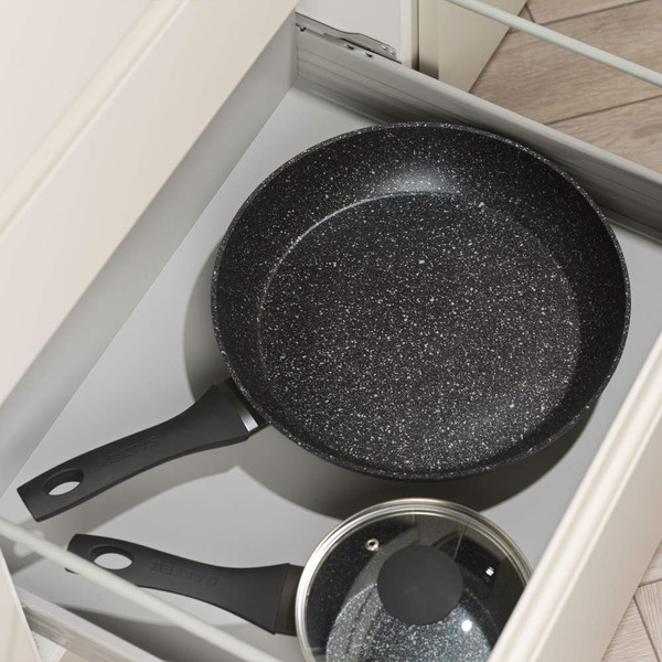 Black speckled non-stick frying pan and glass-lidded pan in kitchen drawer