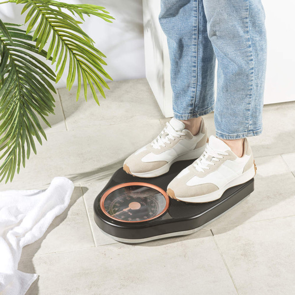 Mechanical bathroom scale with black textured platform and rose gold dial, shown upright