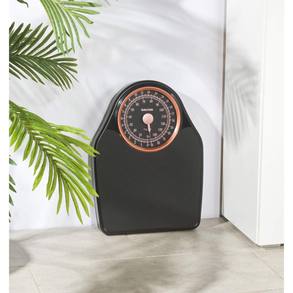 Mechanical bathroom scale with black textured platform and rose gold dial, shown upright