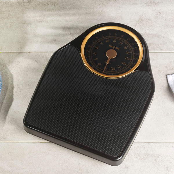 Black digital bathroom scale with textured surface on tiled floor