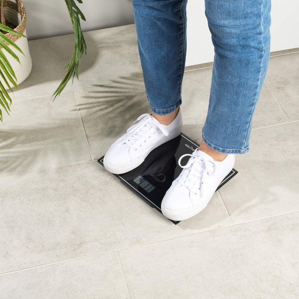 Black Salter digital bathroom scale with display, shown on tiled floor.