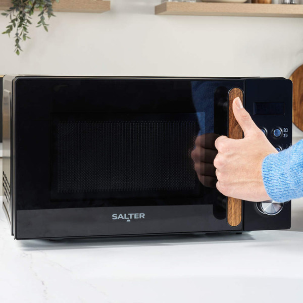 Black Salter microwave with wood-effect handle, hand opening door on a kitchen counter